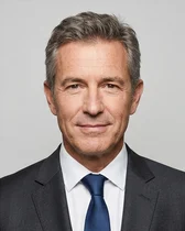 Portrait fictif (image générée par IA) du consultant en réunions : un homme aux cheveux gris, en costume sombre et cravate bleue
